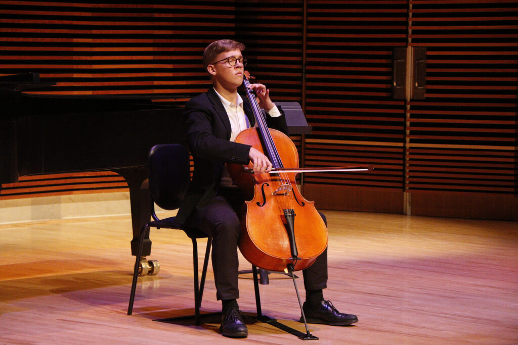 Young man on stage playing the cello