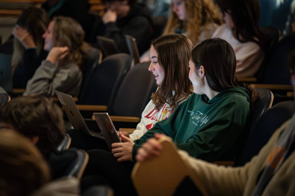 Students sitting in a recital hall looking at a computer