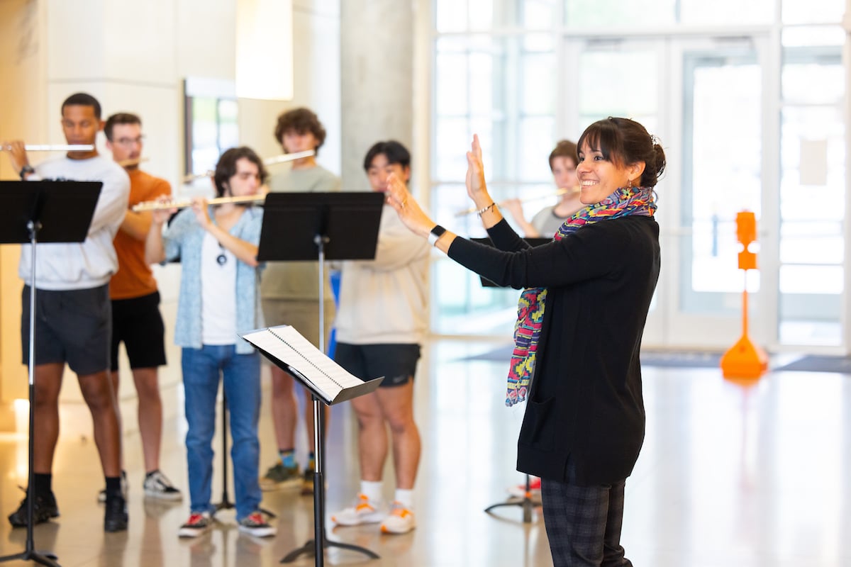 Professor Castillo smiling while she instructs a group of flute students.