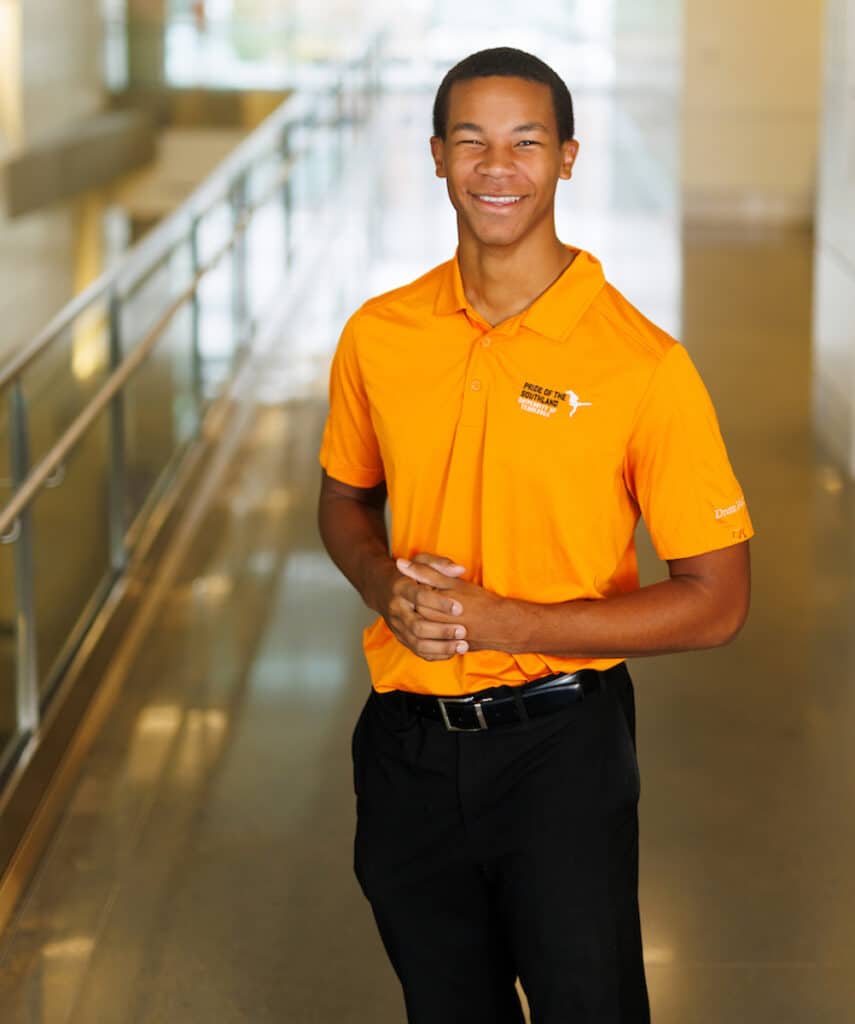 Young man in orange polo smiling