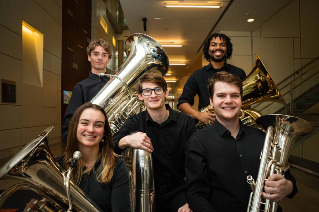 Group of students smiling holding tubas