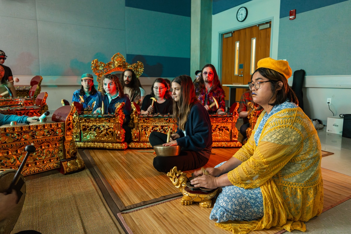Group of students sit and watch the front of the room as they learn gamelan
