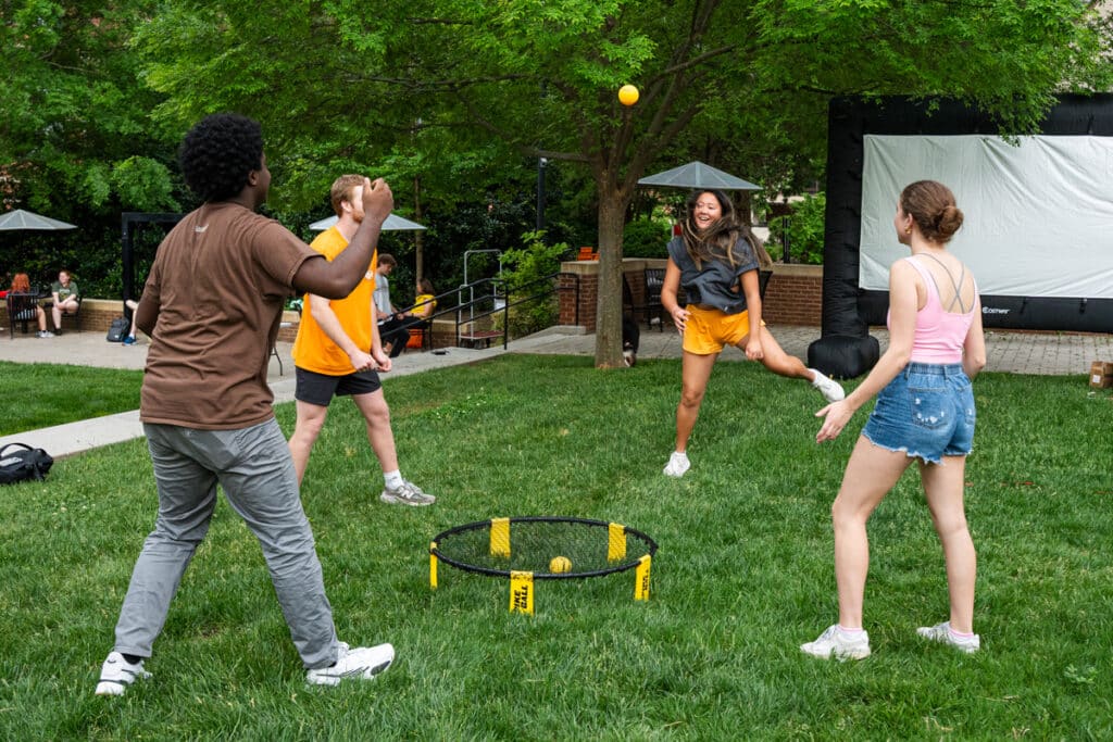 Four students playing a game in the lawn on a summer day