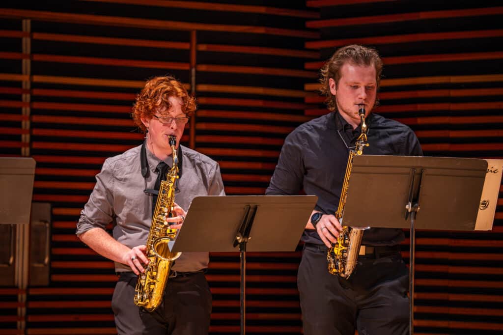Two men on stage playing the saxophone