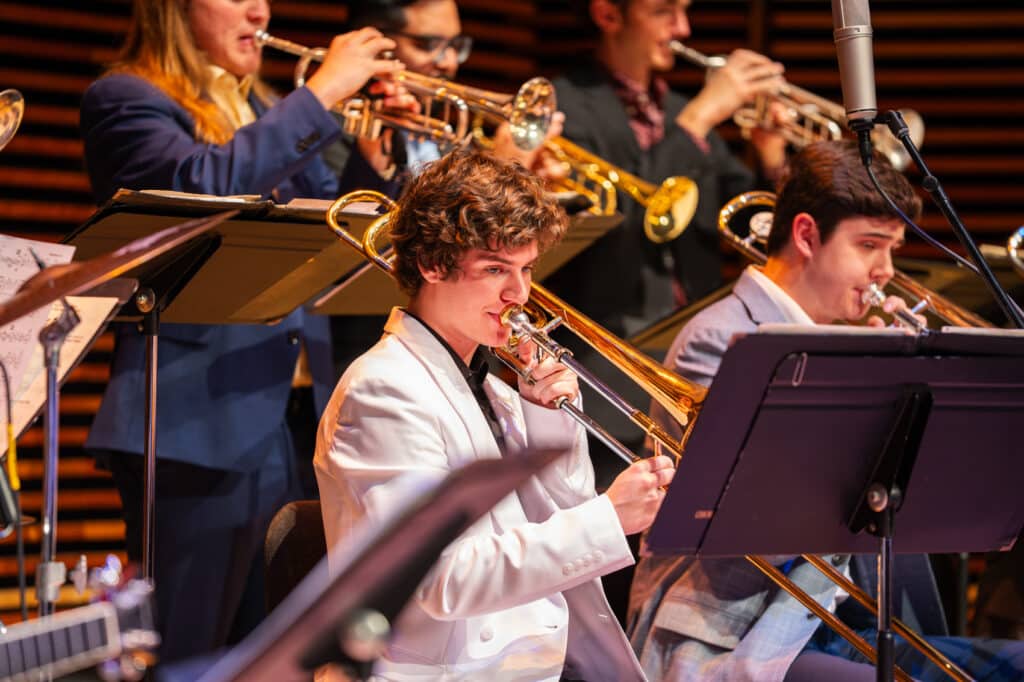 Student playing the trombone sitting down during jazz concert.