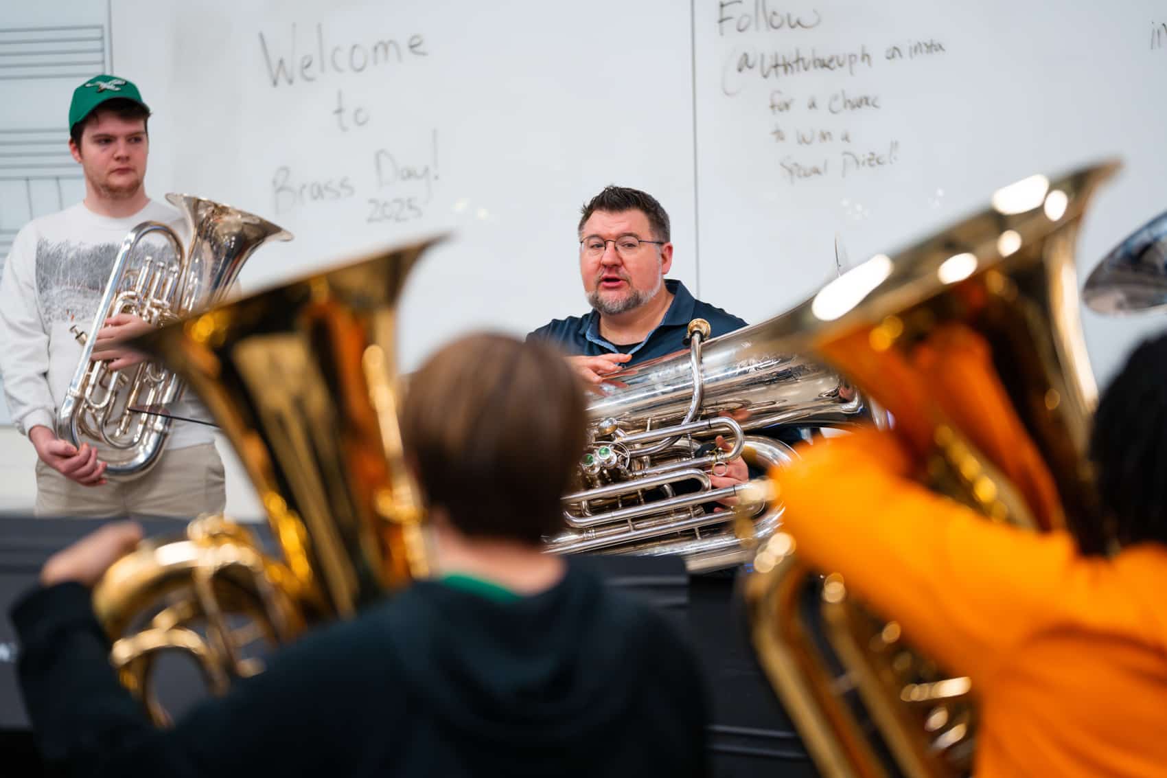 Alex Lapins teaching to a group of students holding tubas