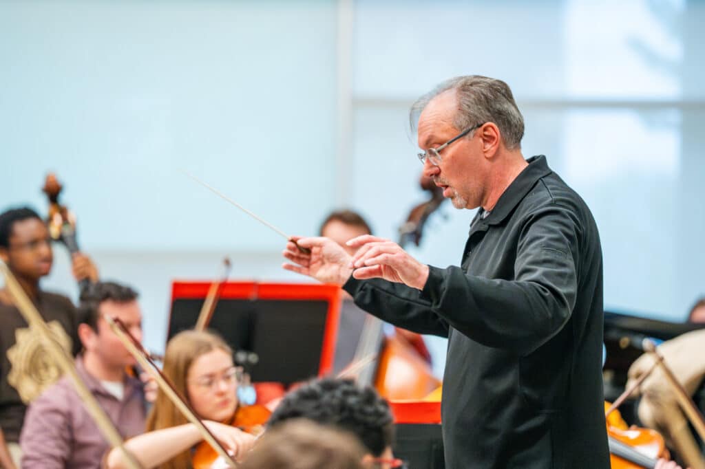 Man conducting in front of students.