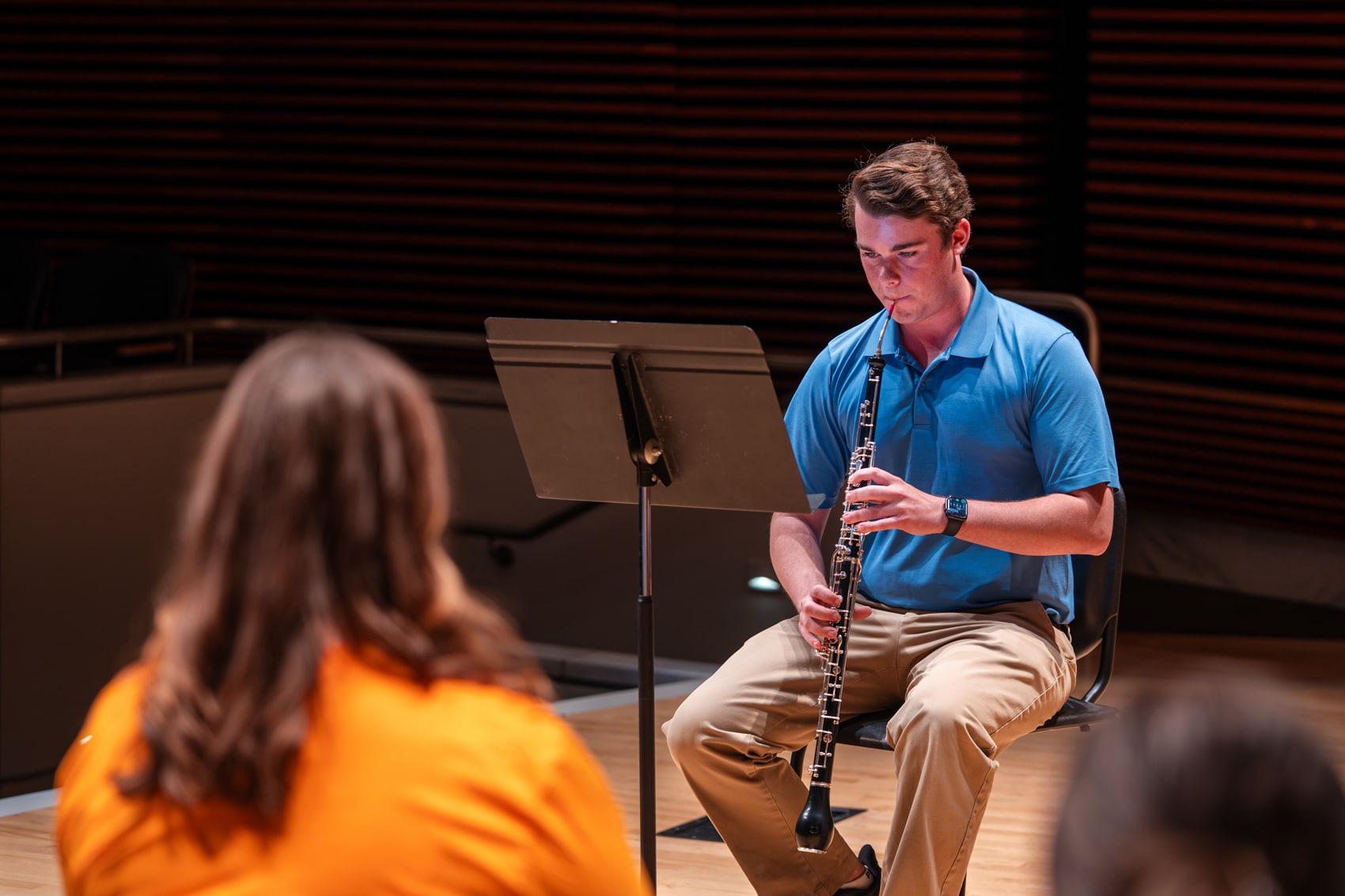 Male student playing the oboe on stage