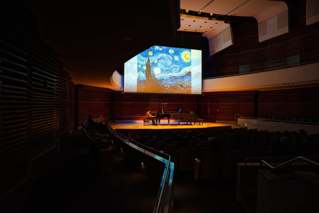 Pianist on stage with a backdrop of Starry Night behind them