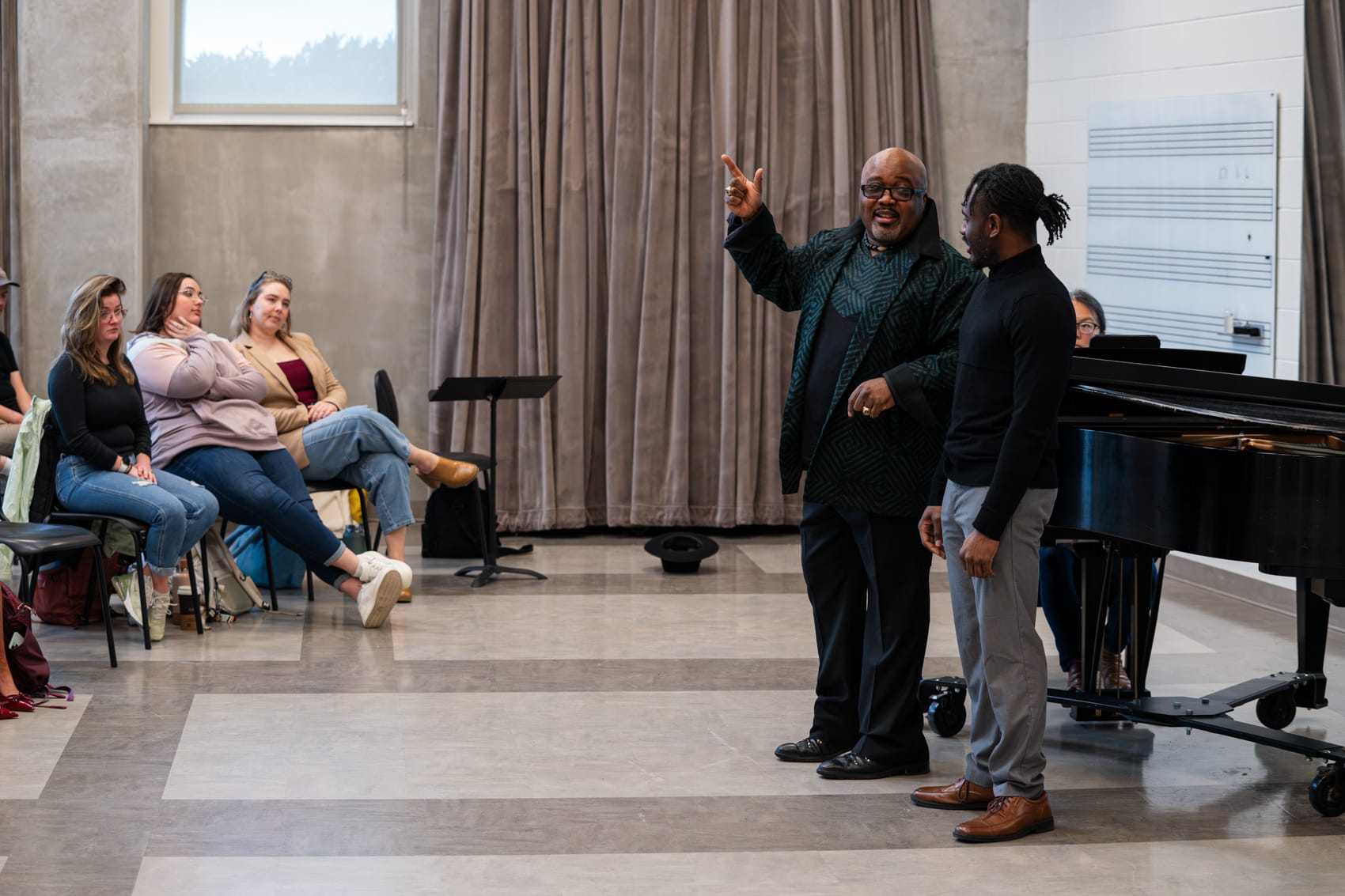 Guest artist coaches male vocalist in front of peers in classroom