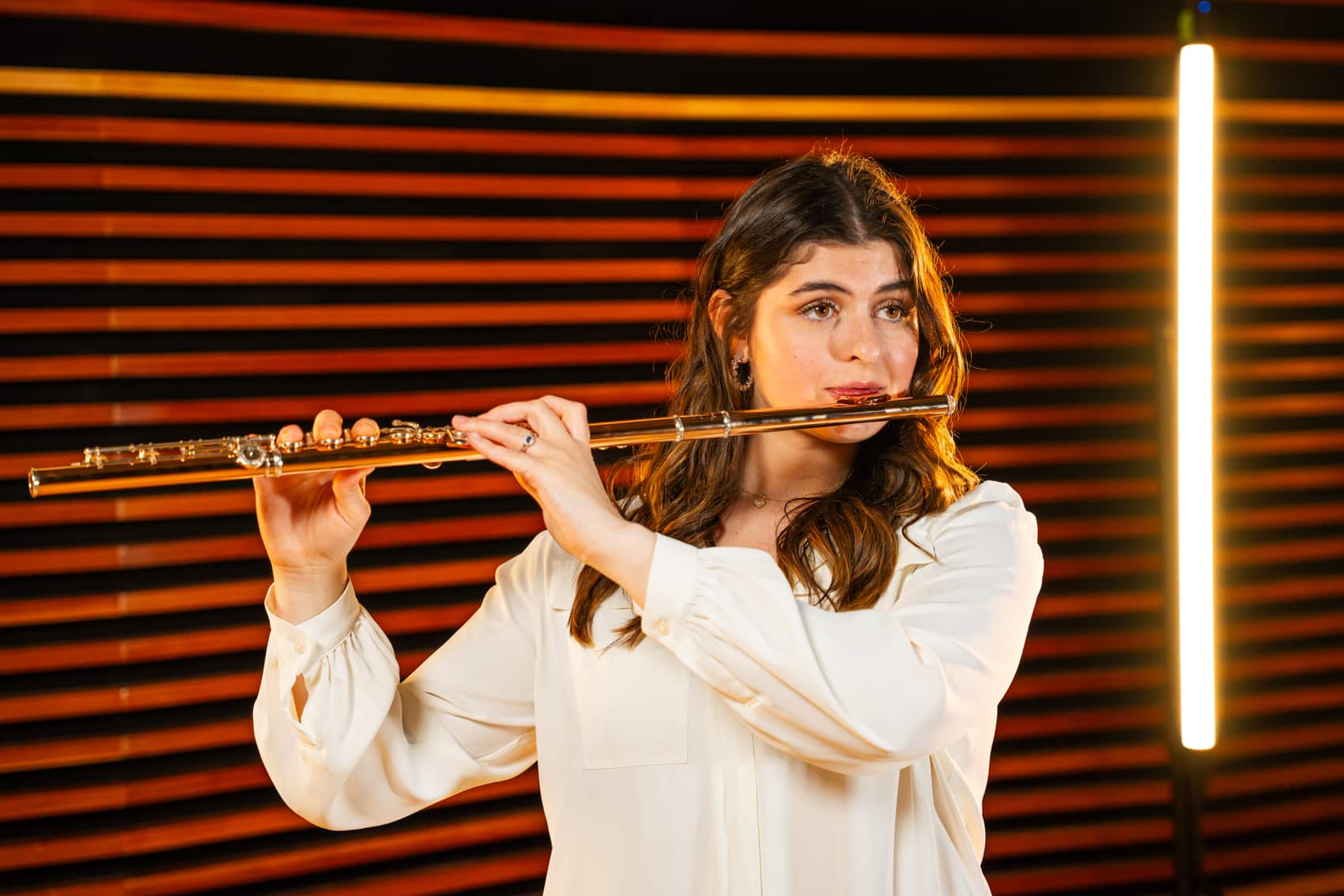 Photo of female student playing the flute on stage.