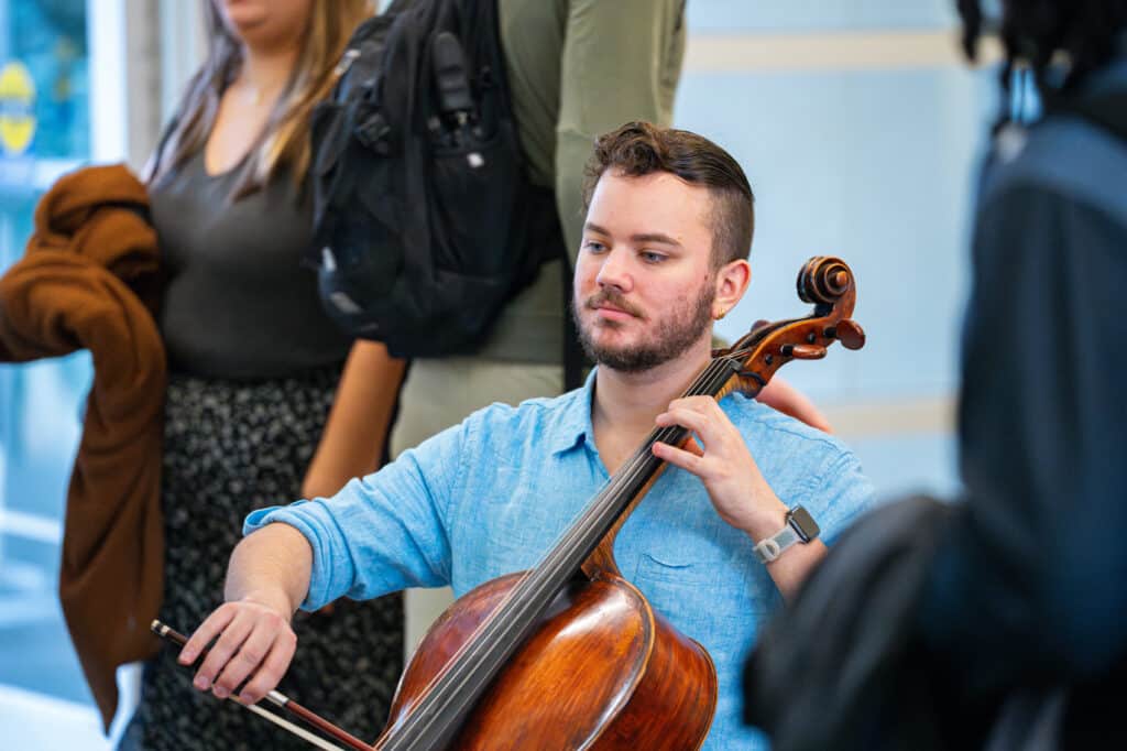 Male student plays cello in lobby