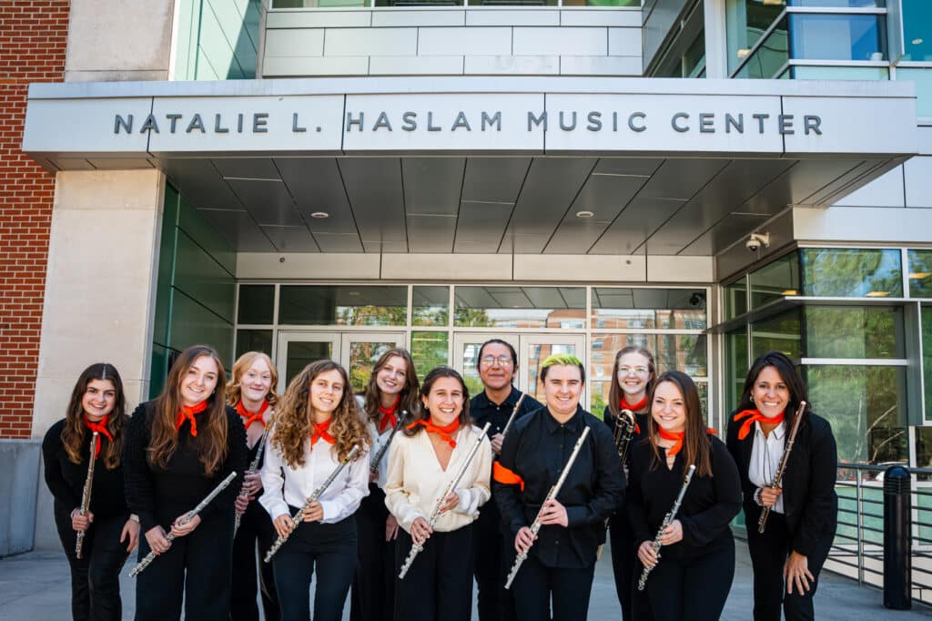 Group photo of students and professor with flutes in front of music building