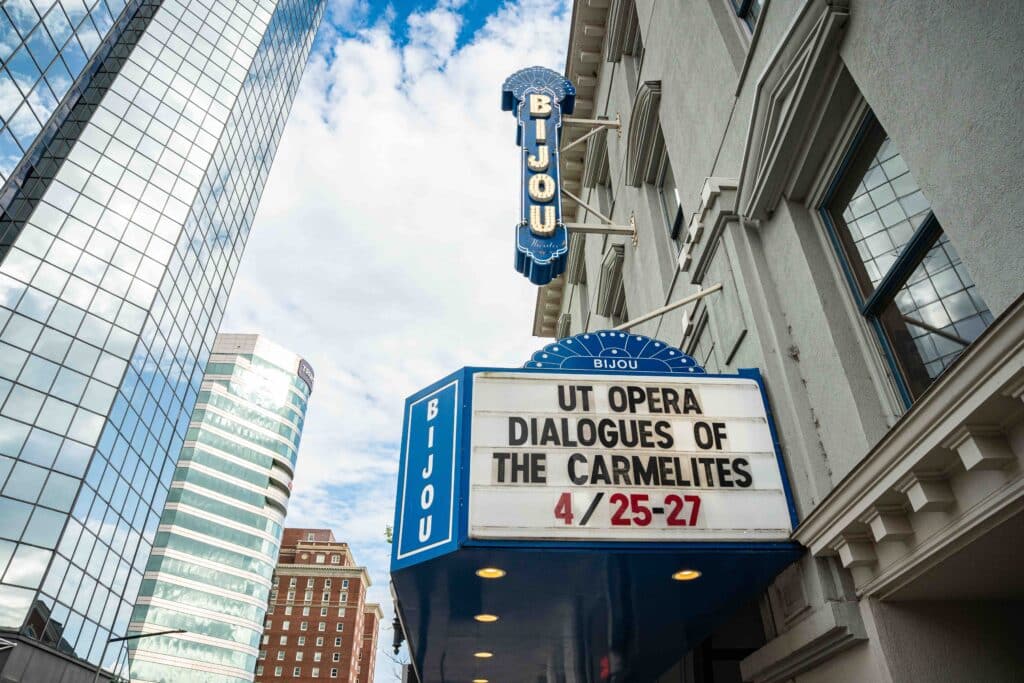 Exterior of Bijou with sign and "UT Opera Dialogues of the Carmelities 4/25-27" written on the marquees.