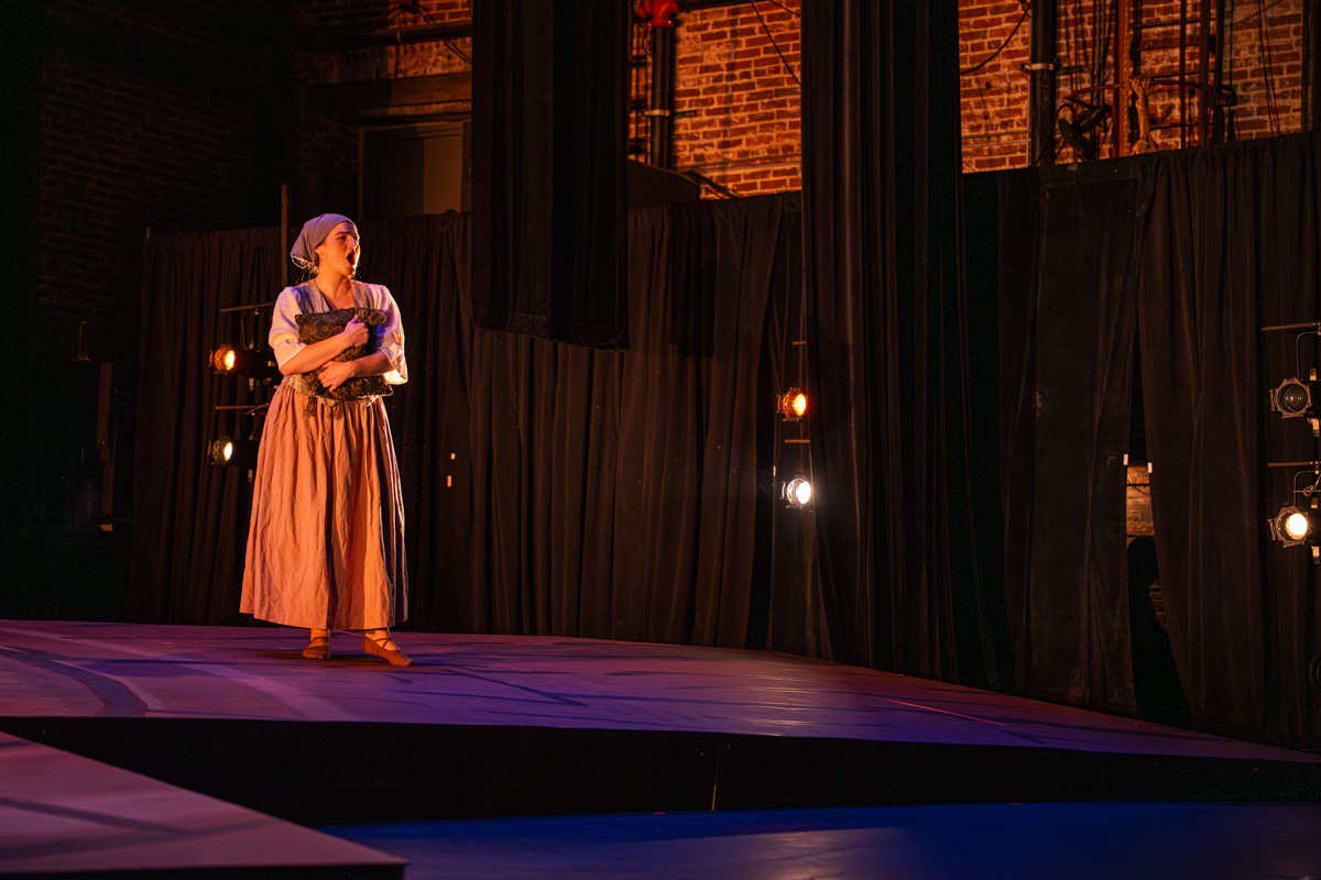 Female student singing on stage during opera performance