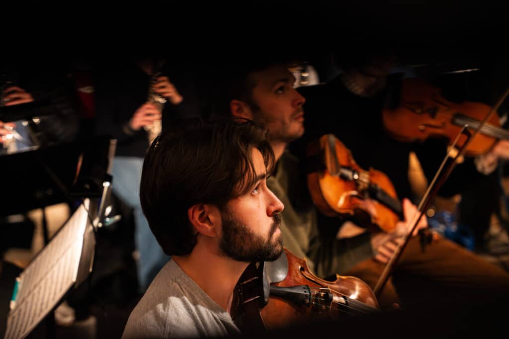 Opera orchestra prepares to play, watching conductor
