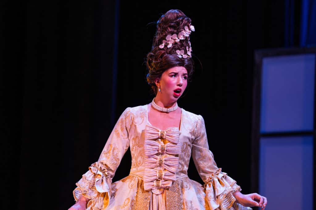 Female opera singer on stage singing while looking to the side