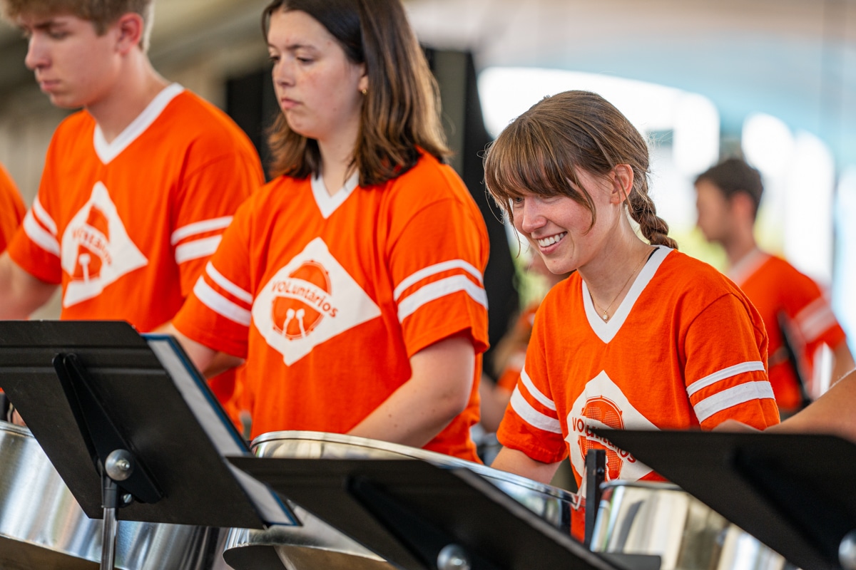 Student smiles while playing the steel drum