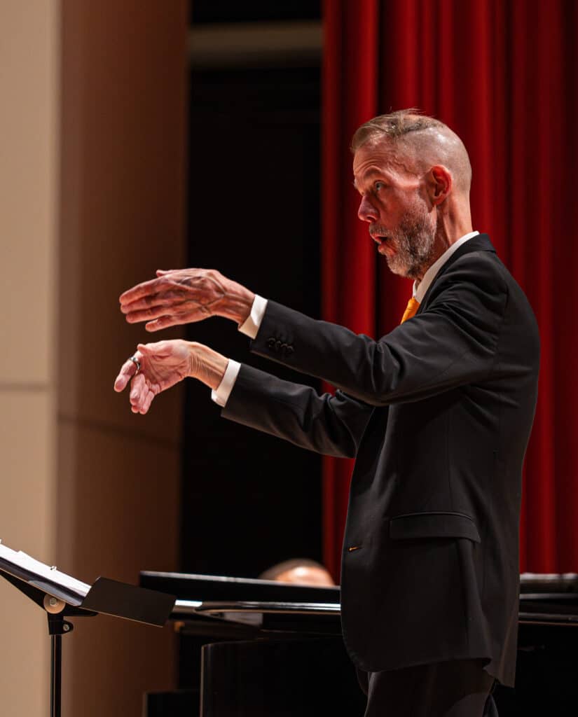 Man conducting choir on stage.