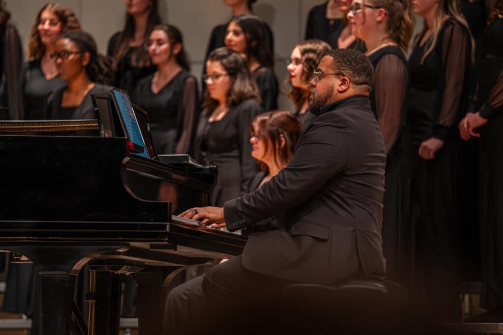 Photo of pianist alongside choir singers.