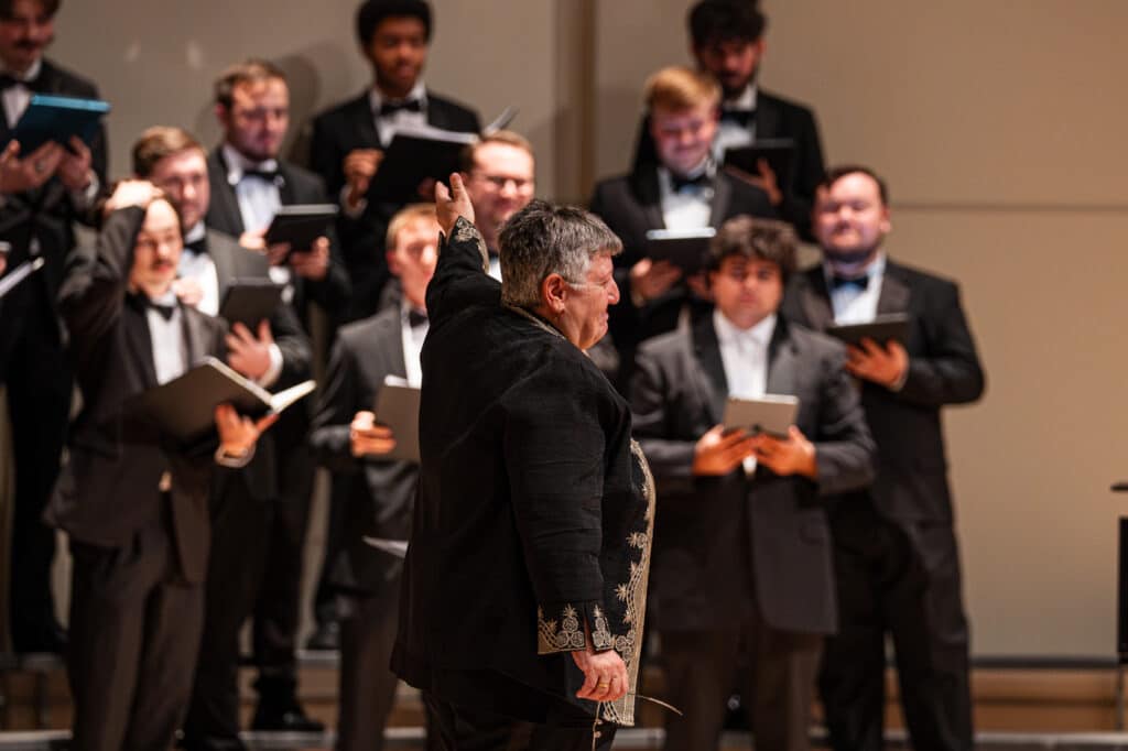 Female conductor points to choral group behind her