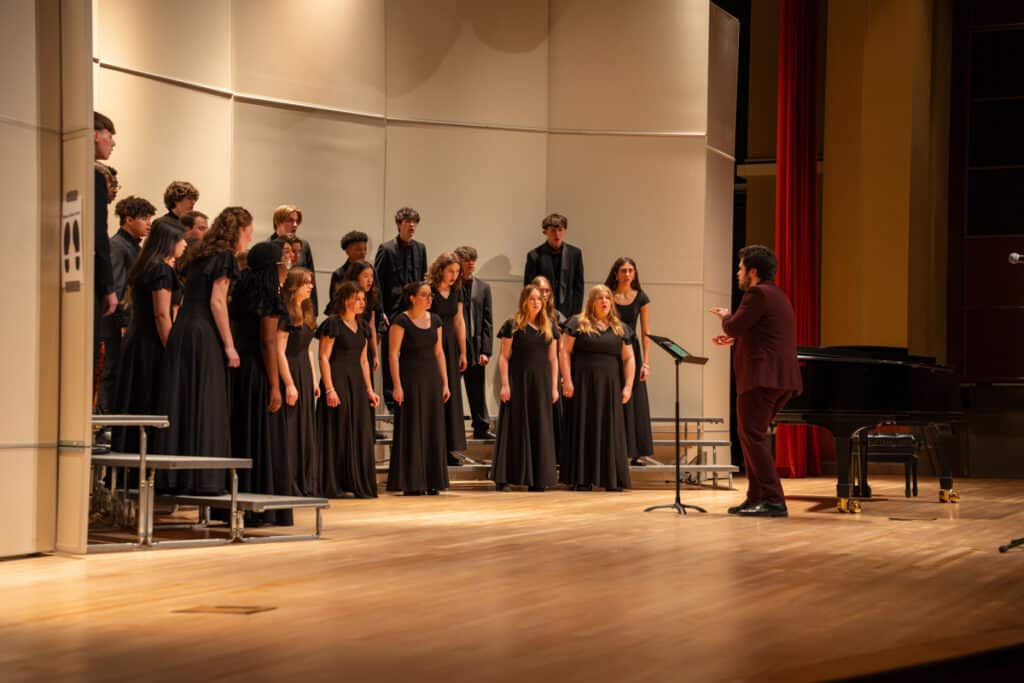 Male conductor on stage leading choir