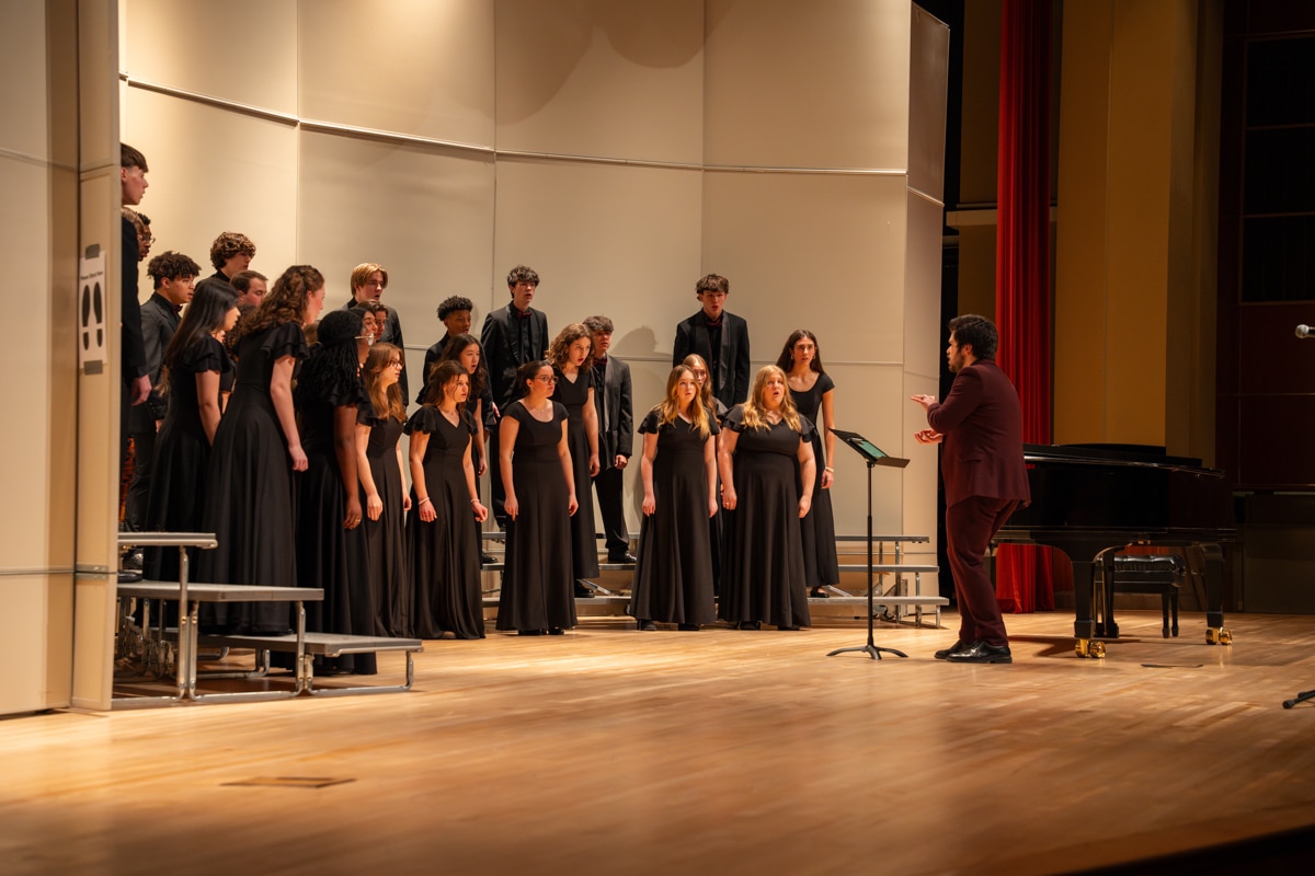 Male conductor on stage leading choir