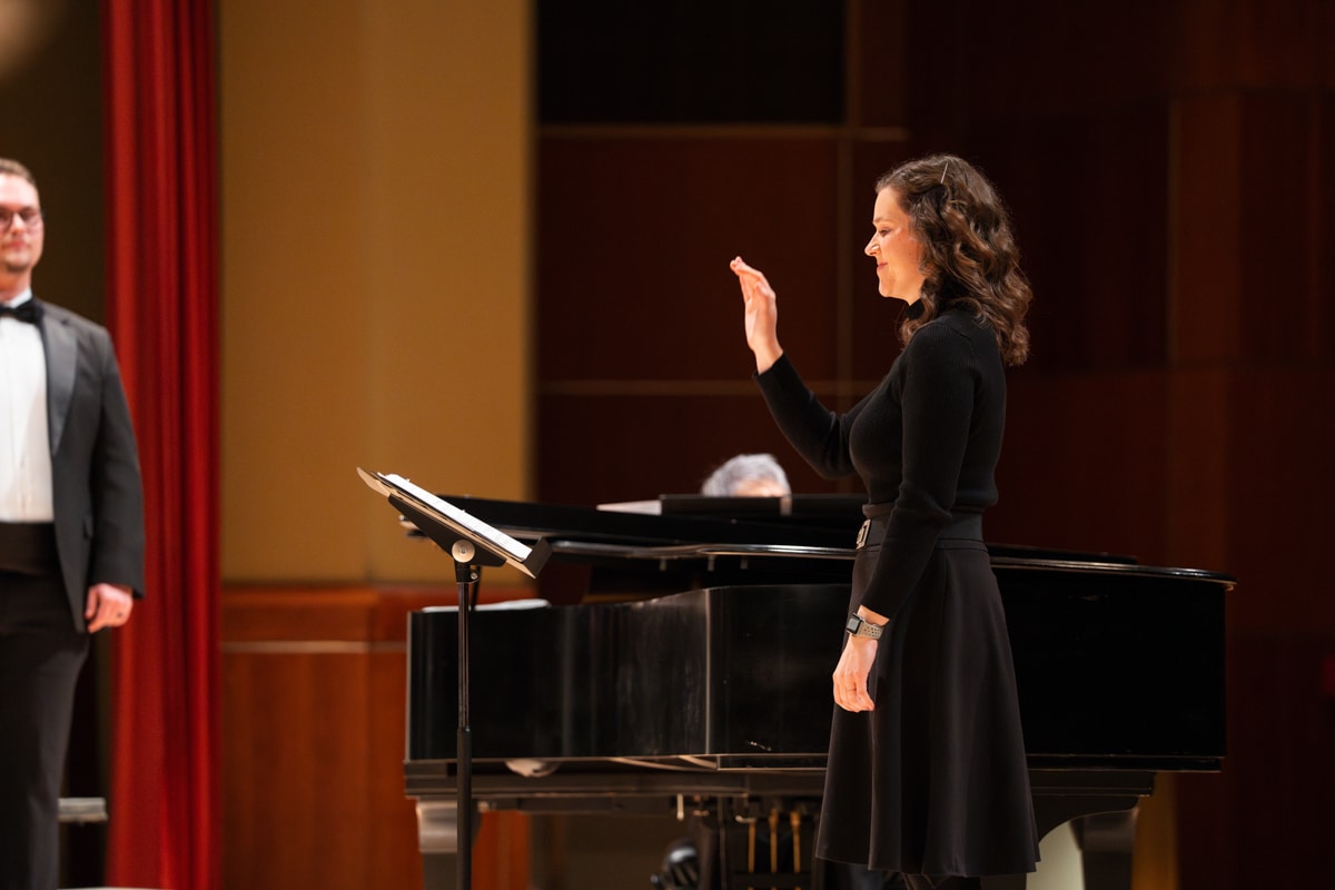 Female conductor in front of choir smiling