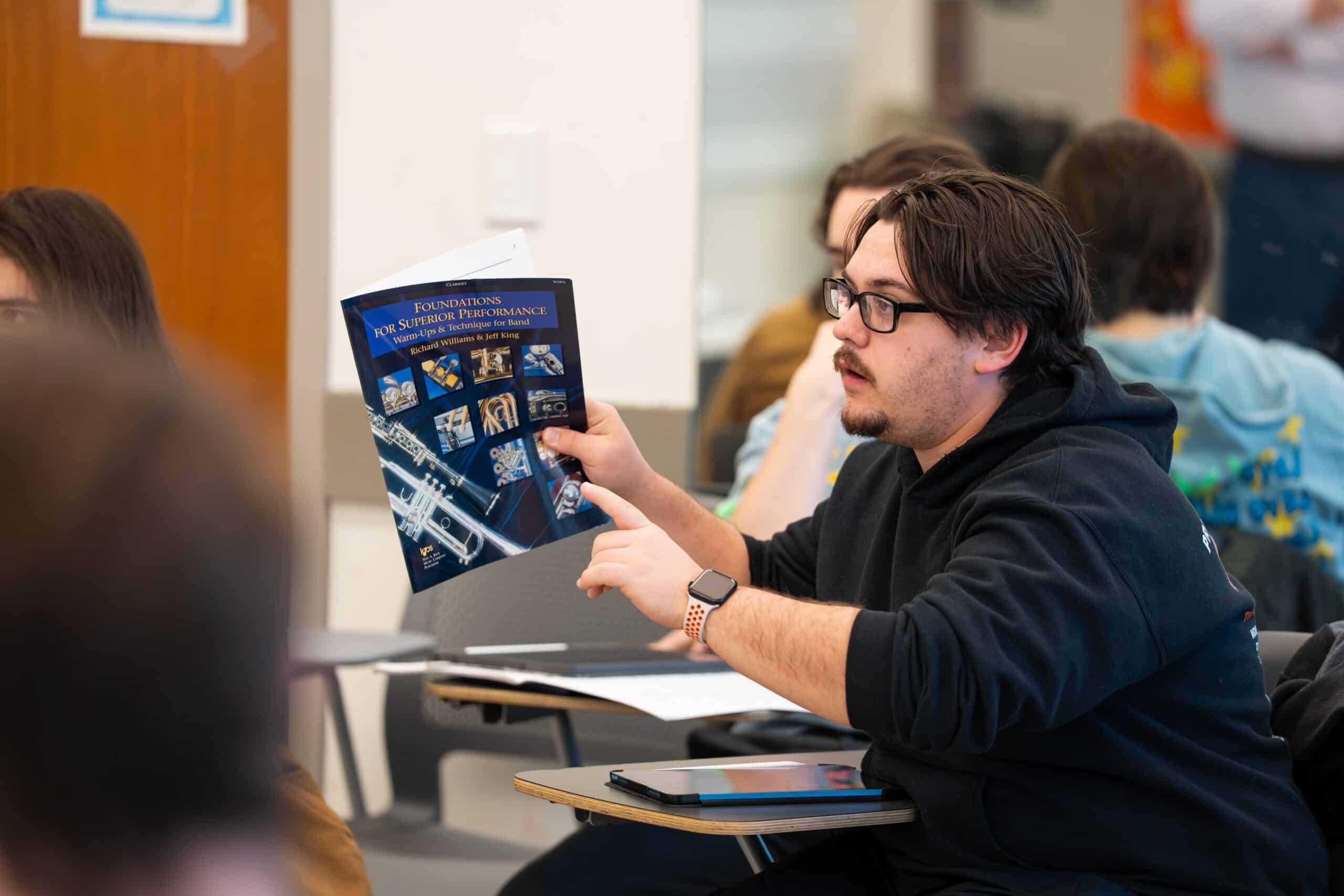Student pointing to textbook, "Foundations for Superior Performance", in Professor O'Leary's class.