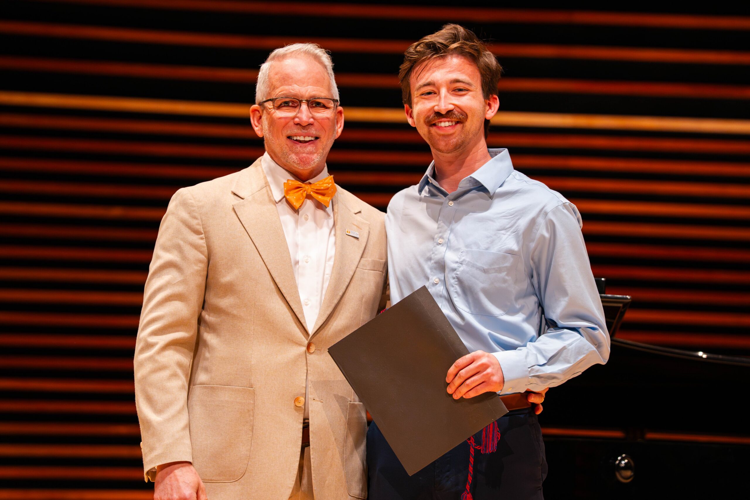 Student smiling with dean holding an award