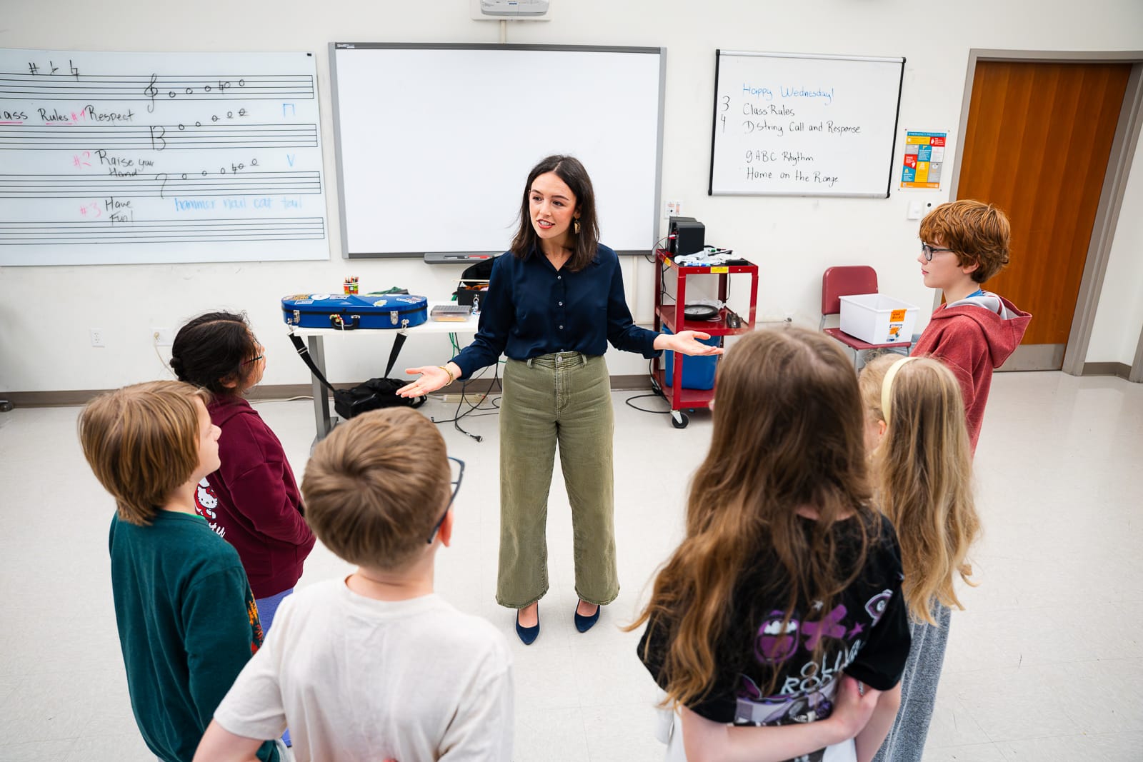 Young female teacher in front of classroom talking to students